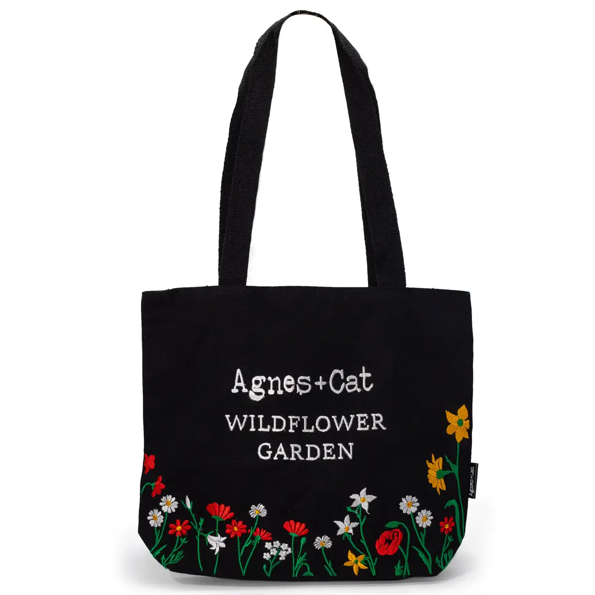 Svart bomullstote med broderade röda, vita och gula vildblommor och texten Wildflower Garden