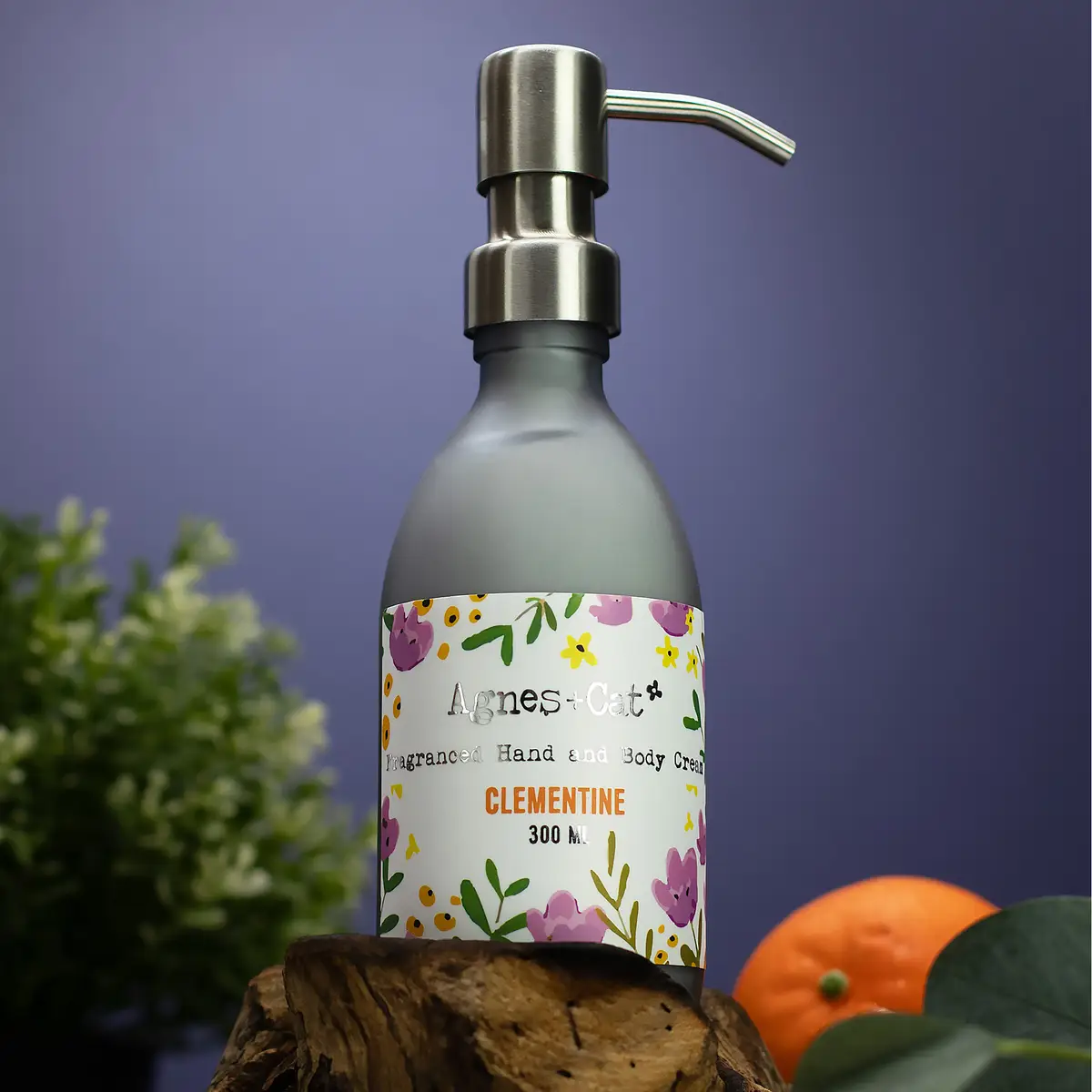Pumpflaska med Agnes + Cat hand- och kroppskräm Clementine 300 ml med blommönster på etiketten