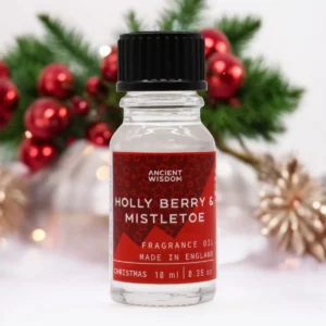 Flaska med Ancient Wisdom doftolja 10 ml Holly Berry & Mistletoe med juldekoration i bakgrunden