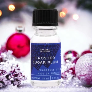 Flaska med Ancient Wisdom doftolja Frosted Sugar Plum 10 ml med juldekorationer i bakgrunden