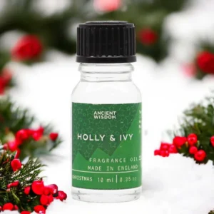 Flaska med Ancient Wisdom Holly & Ivy doftolja 10 ml omgiven av juldekorationer med röda bär och gröna blad