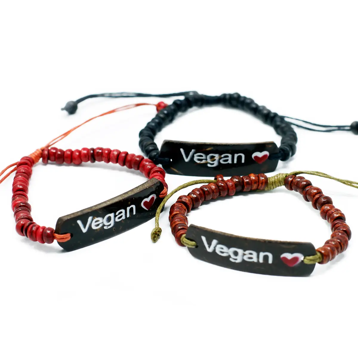 Tre armband med kokosnötskulor och svart platta med vitt budskap 'Vegan'