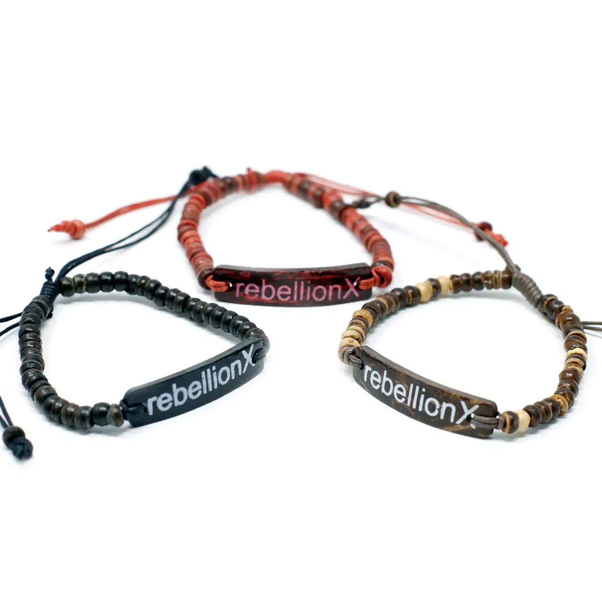 Tre armband med pärlor och budskapet rebellionX på en rektangulär platta