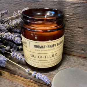 Brunt glasljus med etikett Aromatherapy Candle Be Chilled och lavendelblommor runtom