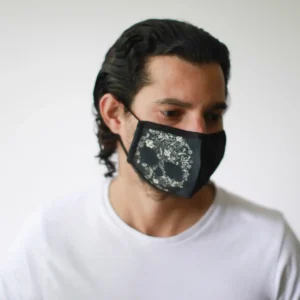 Man med svart återanvändbar ansiktsmask med blommigt dödskallemotiv