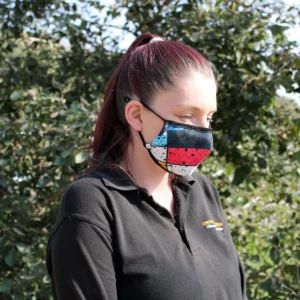 Vuxen person som bär en återanvändbar ansiktsmask med färgglatt graffiti-mönster utomhus