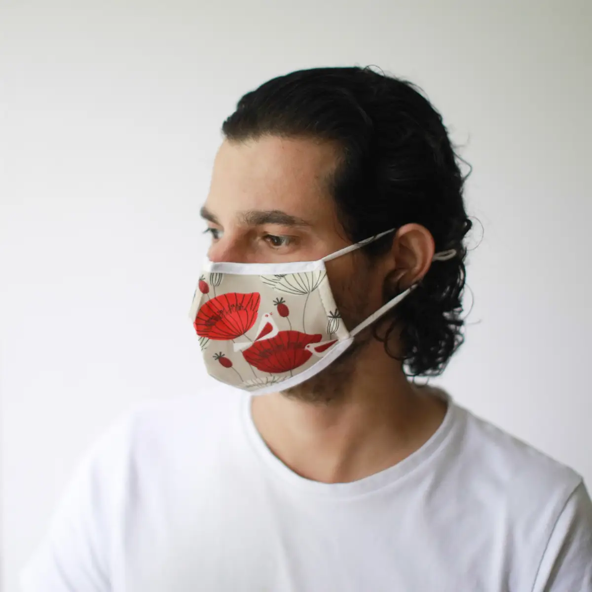 Vuxen man med återanvändbar modeansiktsmask i bomull med rött Oriental Poppies-mönster