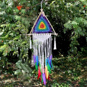Flerfärgad pyramidformad drömfångare hängande bland gröna löv