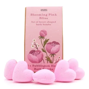 Fem rosa hjärtformade badbomber framför en rosa presentask med blommotiv
