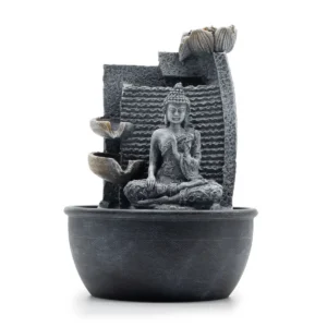 Bordsvatteninstallation med sittande Buddhafigur framför stenliknande bakgrund och lotusformade skålar