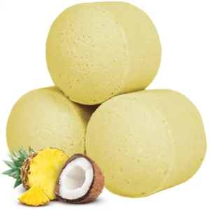 Tre gula badbomber med ananas och kokos vid sidan