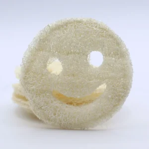 Närbild på en rund, naturlig loofah med leende ansikte i beige färg