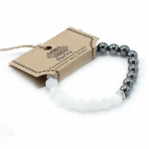 Fasetterat armband med magnetiska svarta pärlor och vita bergkristallpärlor på vit bakgrund