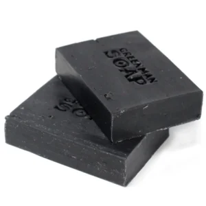 Två svarta tvålstänger med texten Greenman Soap präglad