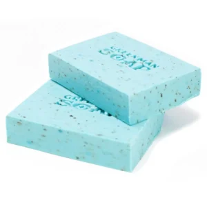 Två ljusblå tvålstänger med små mörka partiklar och texten Greenman Soap