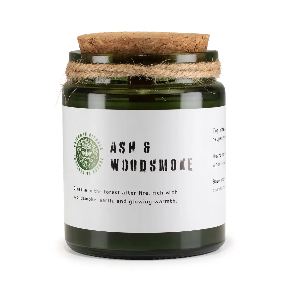Grönt glasljus med korklock och vit etikett med text Ash & Woodsmoke