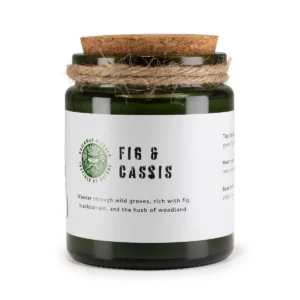 Grönt glasljus med korklock och etikett med texten Fig & Cassis