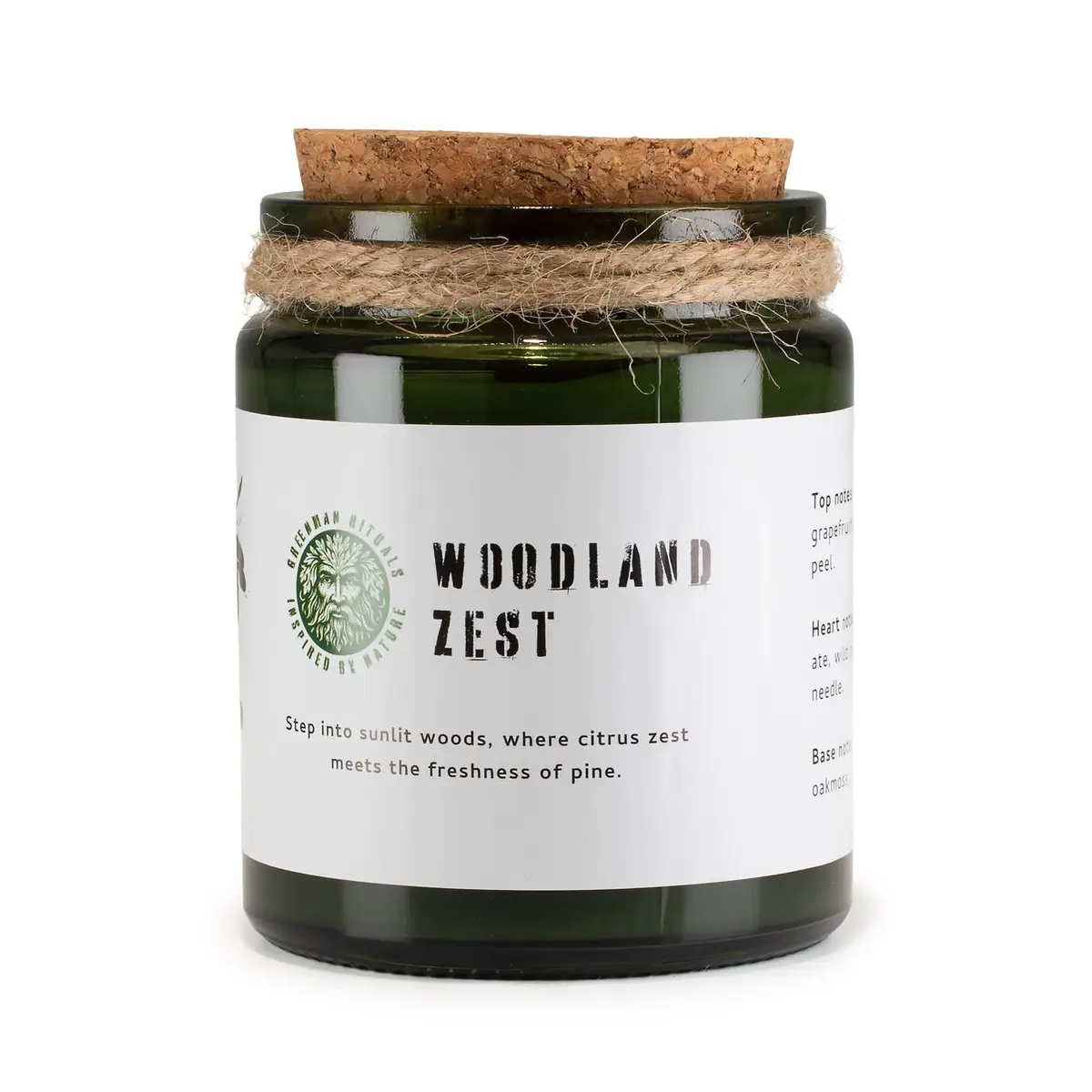 Grönt glasljus med korklock och vit etikett med text Woodland Zest från Greenman Woodwick