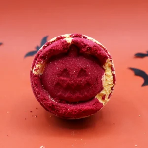 Röd och orange Halloweenbadbomb med ansikte på orange bakgrund med fladdermöss