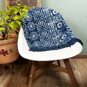 Indigoblå pläd med vita mönster och fransar på vit stol i rum med växt