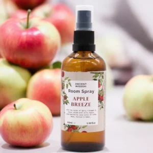 Brun flaska med hemfräsch rumsspray Apple Breeze omgiven av röda och gröna äpplen