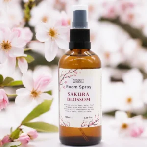 Brun glasflaska med rumsspray Sakura Essence omgiven av körsbärsblommor