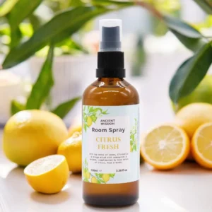 Brun glasflaska med rumsspray Citrus Fresh omgiven av citroner