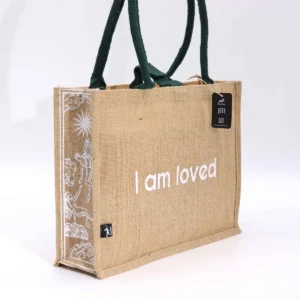 Stor jutesäck i naturfärg med texten I am Loved och gröna handtag
