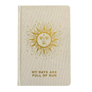 Elfenbensfärgad anteckningsbok med guldfärgad sol och texten 'My Days Are Full of Sun' på framsidan