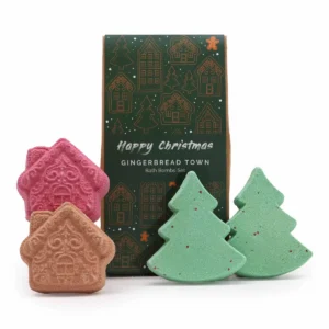 Juligt presentpaket med badbomber formade som pepparkakshus och julgranar framför en grön förpackning med julmotiv