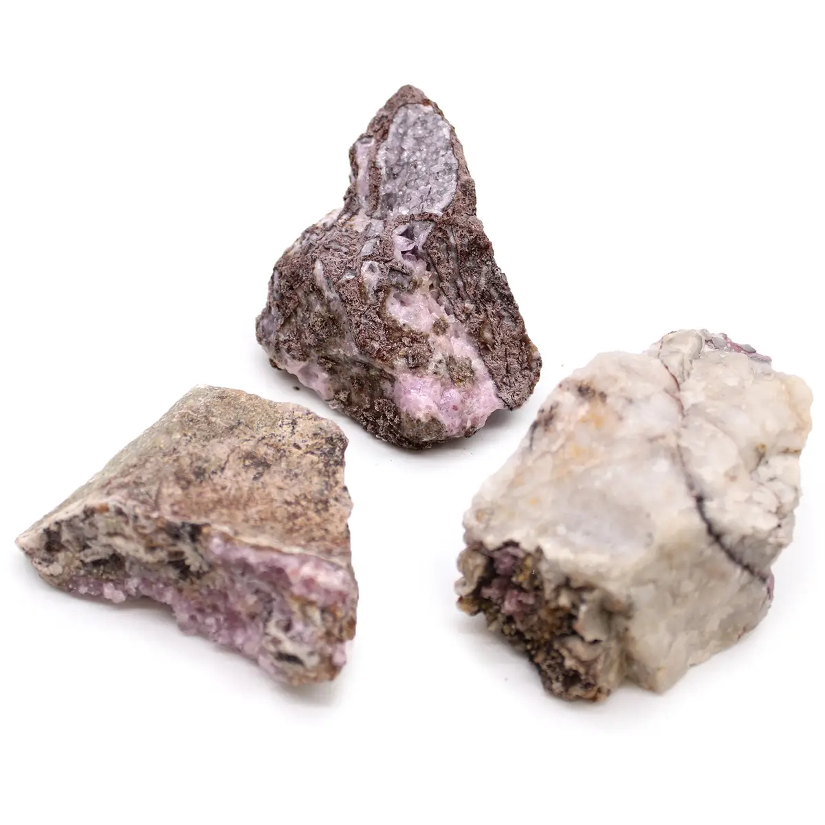 Tre råa mineralprover av koboltcalcit med rosa och lila nyanser på vit bakgrund