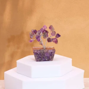 Miniatyrträd med ametiststenar på orgonitbas placerad på vit piedestal