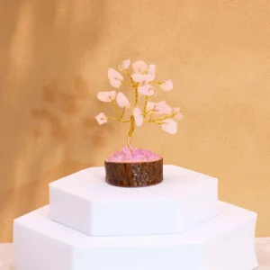 Miniatyrträd med rosa rosenkvartsstenar på träbas placerat på vit piedestal