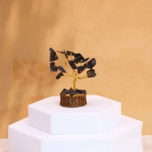 Miniatyrträd med svarta agatstenar på träbas mot beige bakgrund
