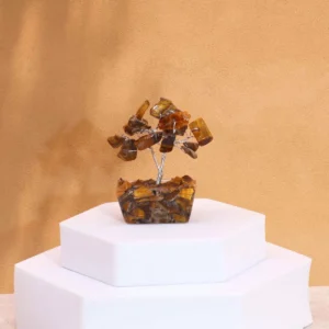 Miniatyrträd av tigeröga på orgonitbas placerat på vit piedestal