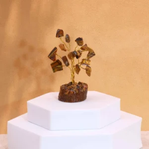 Miniatyrträd med tigeröga-ädelstenar på träbas placerat på vit piedestal