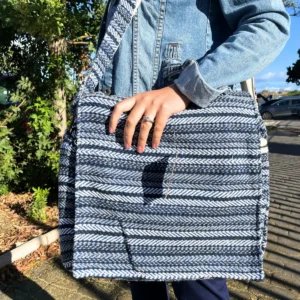 Mjuk laptopväska med blå ränder i Banjara-design, hålls av person i jeansjacka