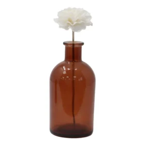 Vit nejlikaliknande doftblomma på brun glasflaska med vasspinne