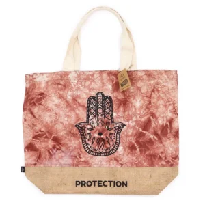 Terrakottafärgad strandväska i jute och bomull med svart Hamsa-symbol och texten Protection