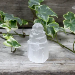 Naturligt selenittorn med mjölkig yta på träyta med gröna blad i bakgrunden