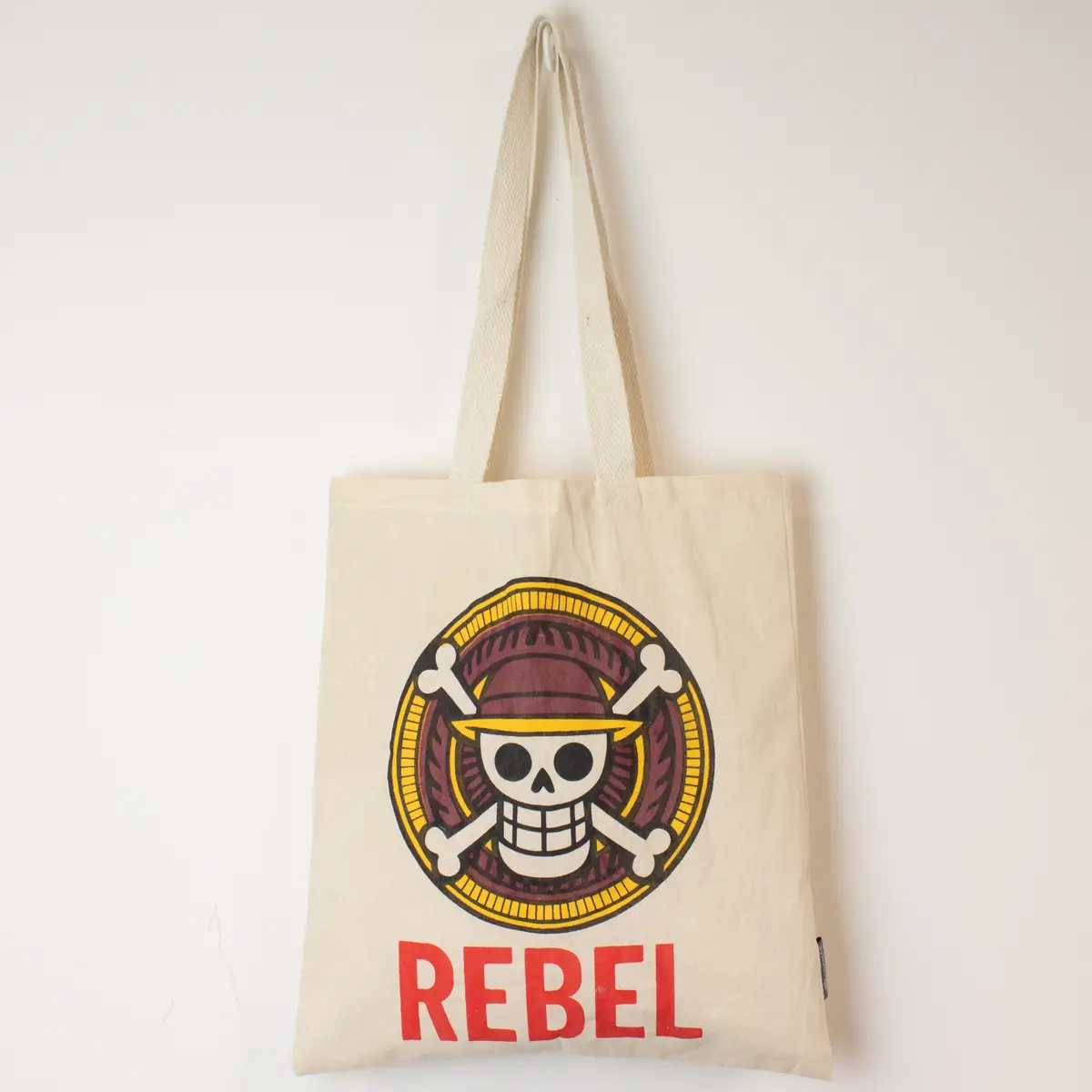 Naturfärgad bomullskasse med färgstarkt REBEL-tryck och långa handtag