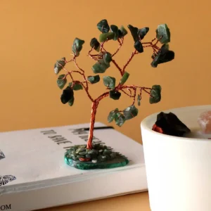 Önsketräd med gröna aventurinstenar på grön agatbas placerat på bok