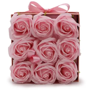 Nio rosa tvålblommor arrangerade i en fyrkantig rosa presentask med rosett