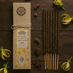 Förpackning med ritualhartser på pinne och gula ylang ylang-blommor på träbord