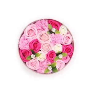 Rund presentask fylld med rosa och vita tvåltrosor och gröna blad