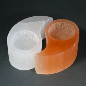 Ying Yang-formad ljusstake i vit och orange selenit på mörk bakgrund
