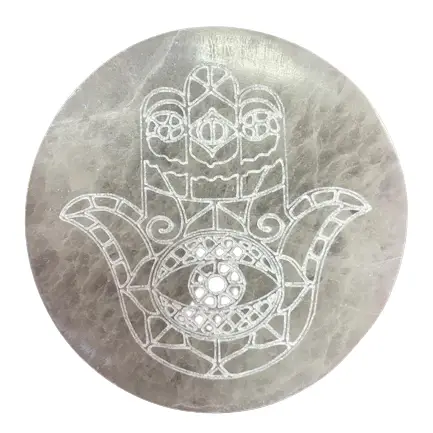 Rund selenitplatta med inristad Hamsa-symbol i vitt
