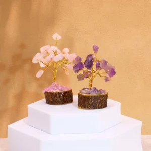 Två miniatyrträd av ädelstenar på träbas, en med rosenkvarts och en med ametist, placerade på vit piedestal