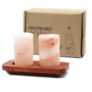 Två shotglas i rosa Himalayasalt på en träbricka med presentförpackning i bakgrunden