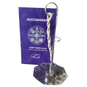 Set med silverpläterad rökelsehållare och reprökelse framför dekorativ ask med Astamangal-symbol